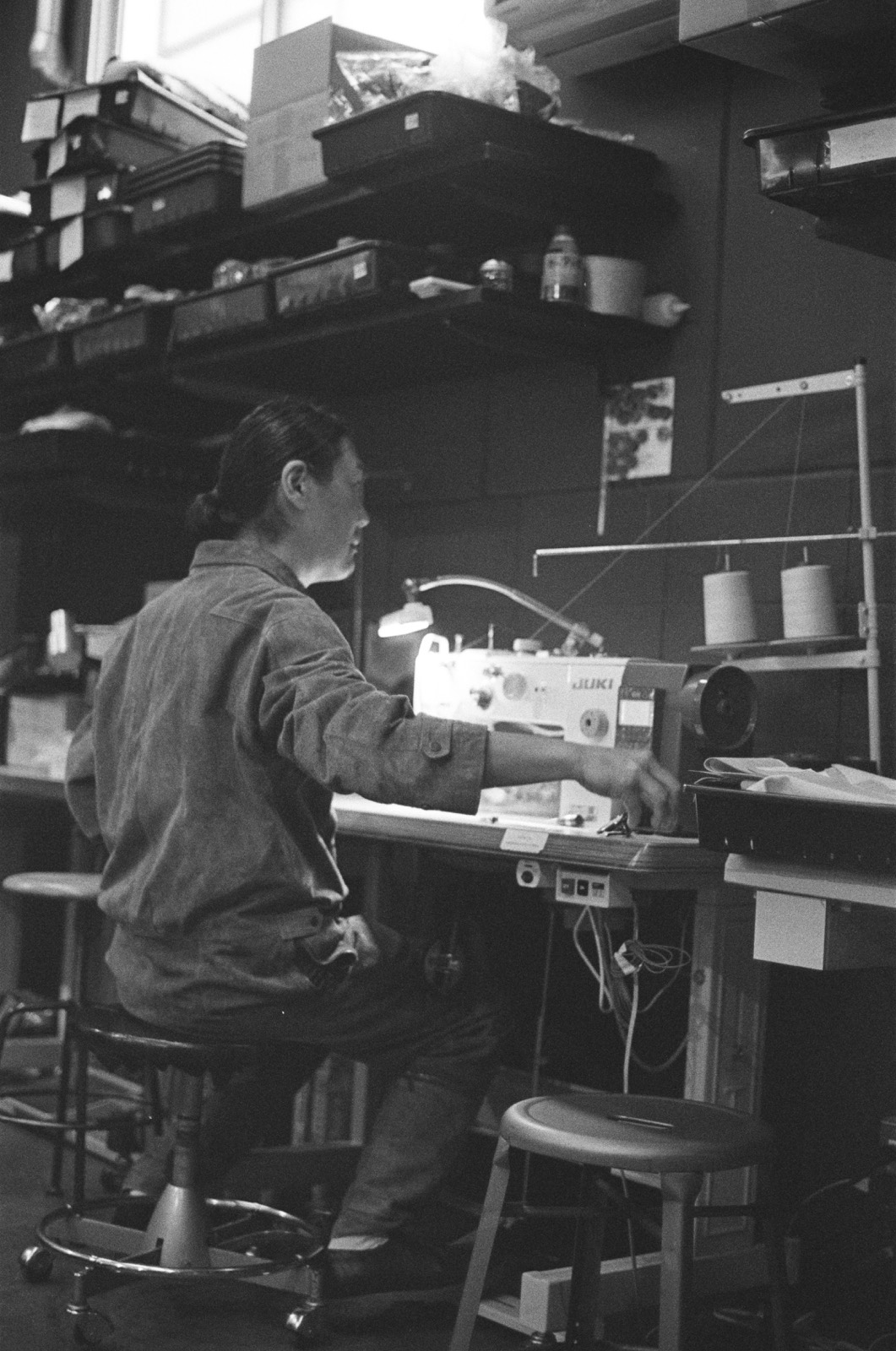 An artisan at an industrial sewing machine in a Japanese workshop